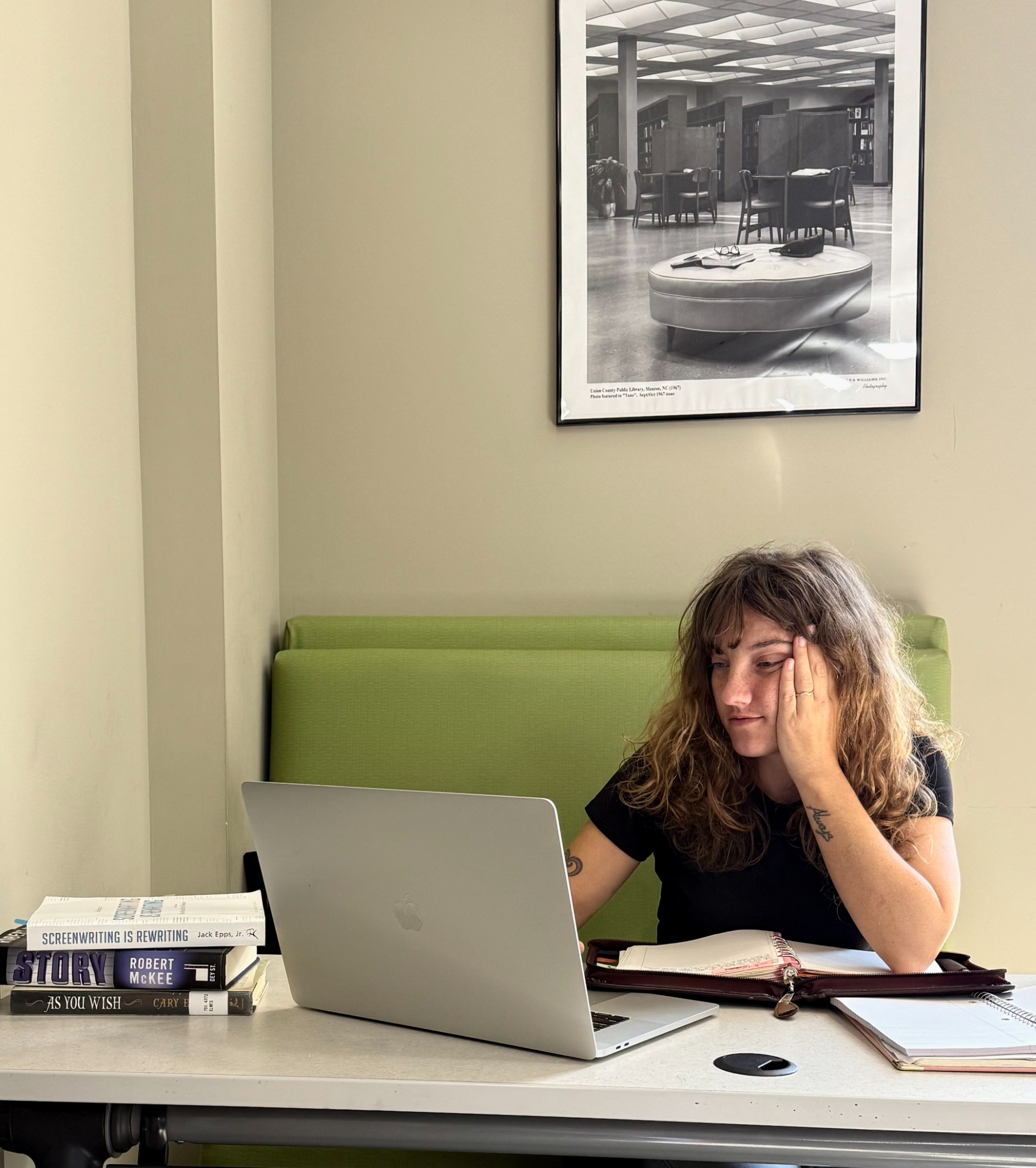 Amanda Pimenta working on a laptop with writing books and an open notebook